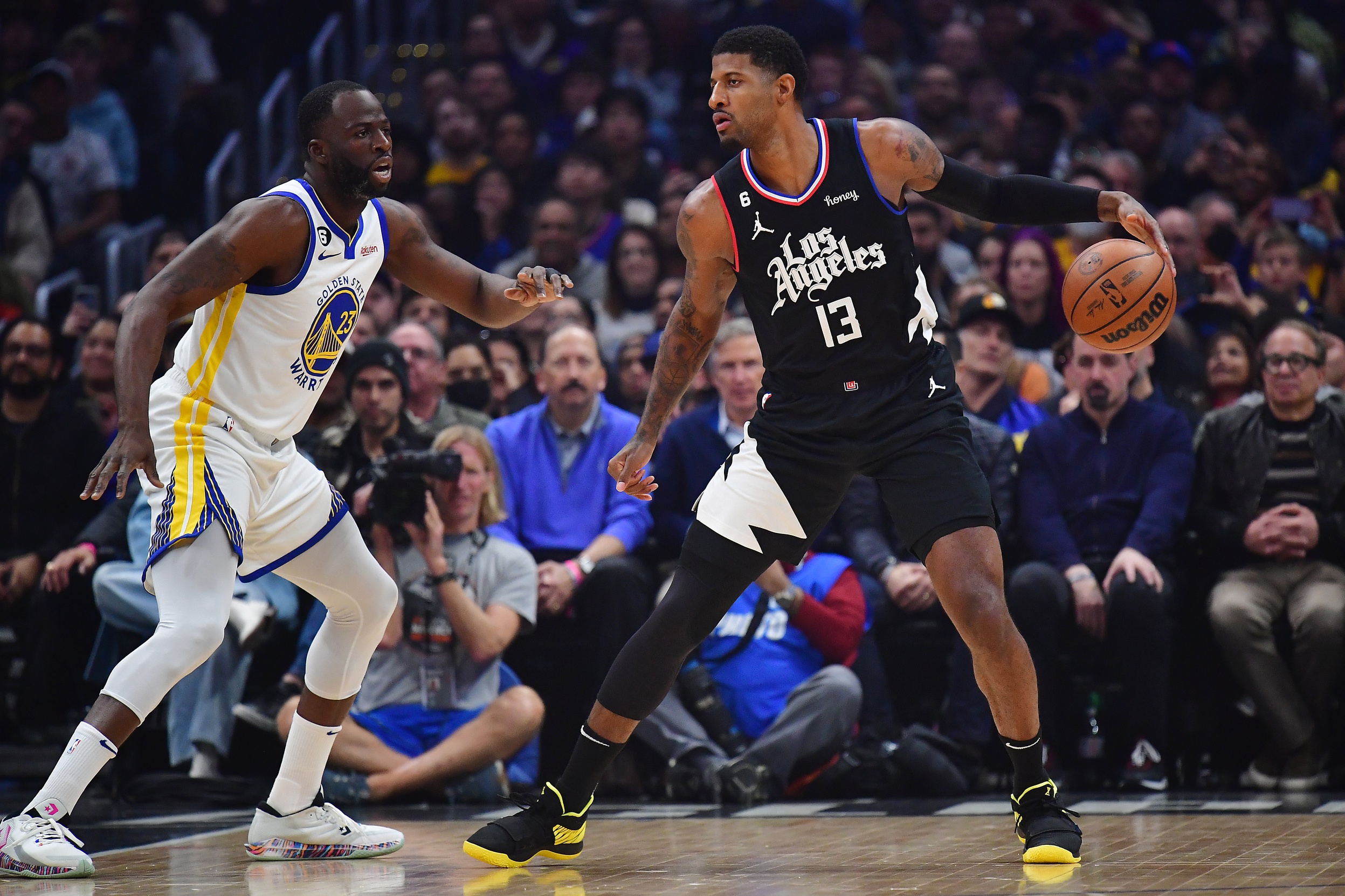 Mar 15, 2023; Los Angeles, California, USA; Los Angeles Clippers forward Paul George (13) moves the ball against Golden State Warriors forward Draymond Green (23) during the first half at Crypto.com Arena. Mandatory Credit: Gary A. Vasquez-USA TODAY Sports
